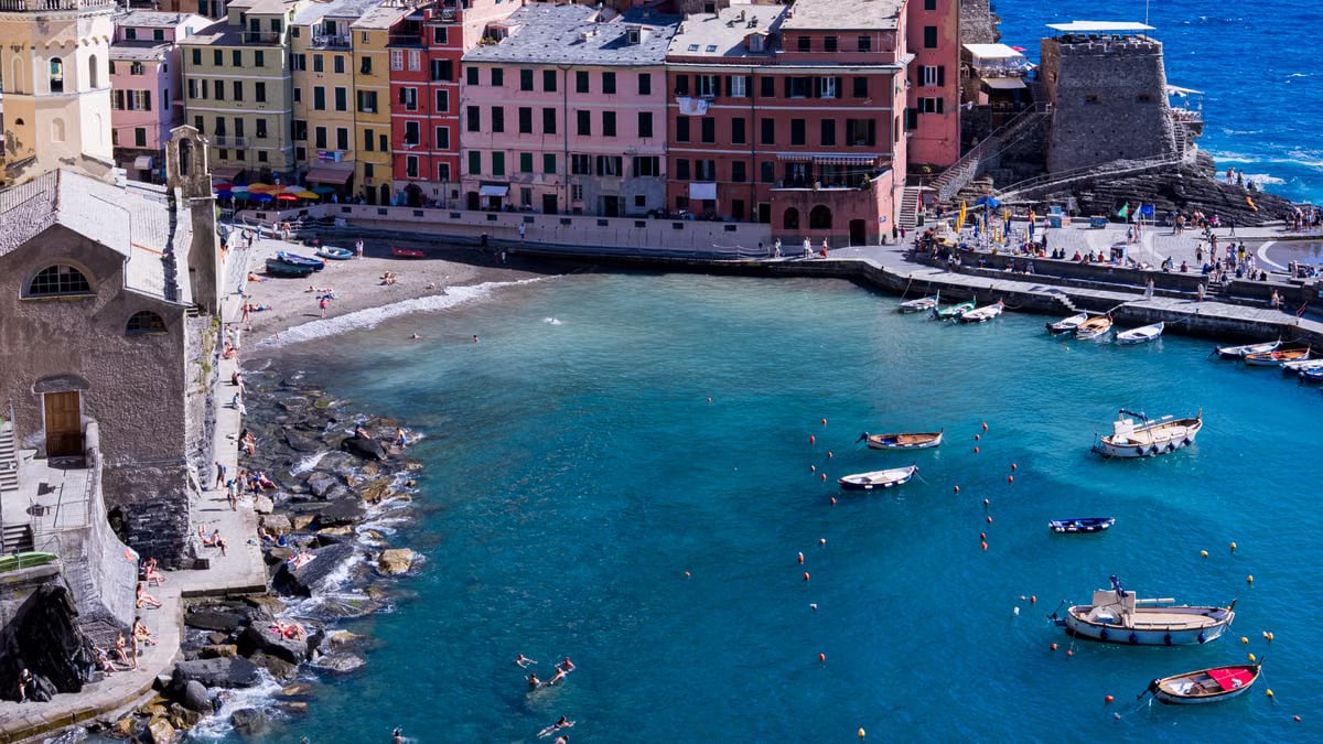 Aerial view of Vernazza harbor with colorful buildings and boats in Liguria, Italy.